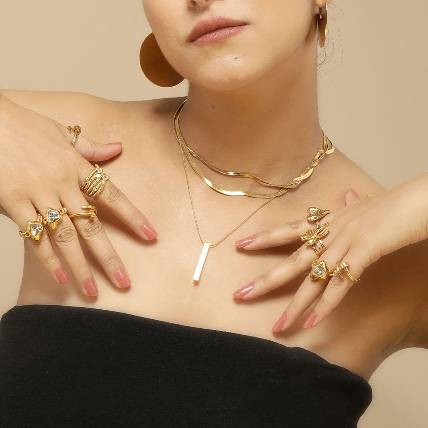 A woman wearing layered gold necklaces and rings