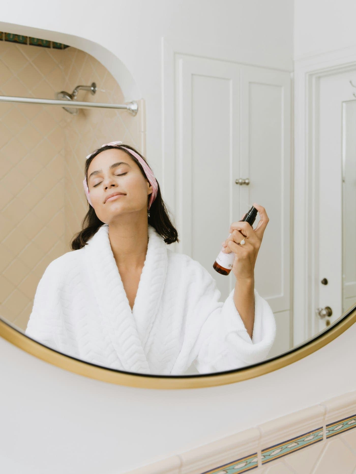 A woman applying skincare at a mirror